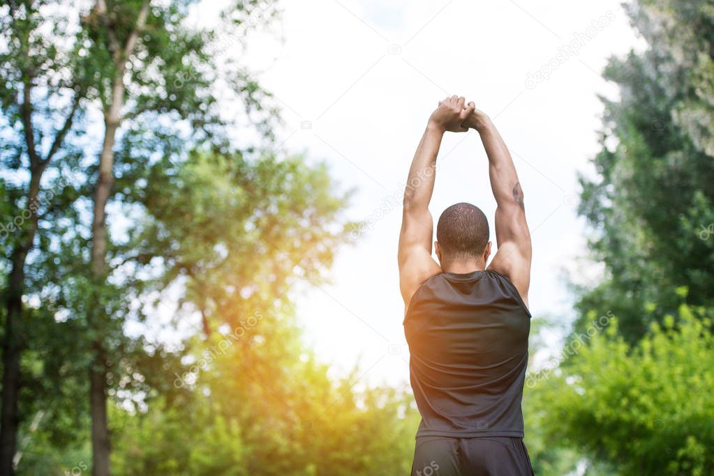 african american sportsman stretching in park 