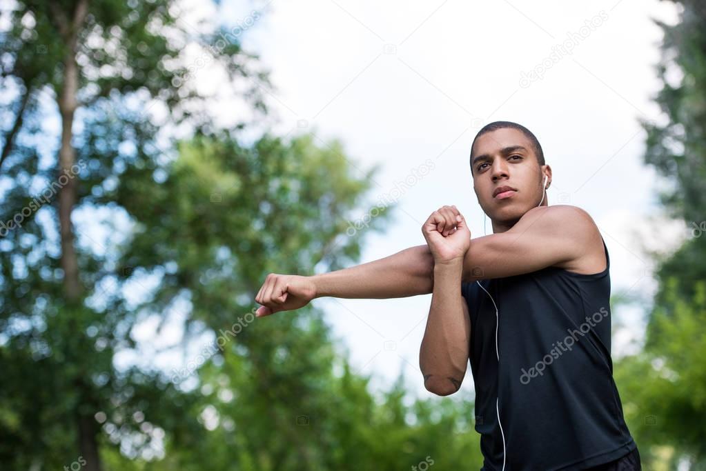 african american sportsman stretching in park 