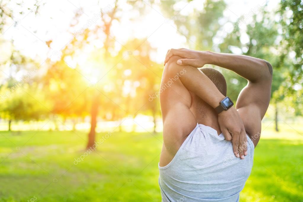 african american sportsman stretching in park 