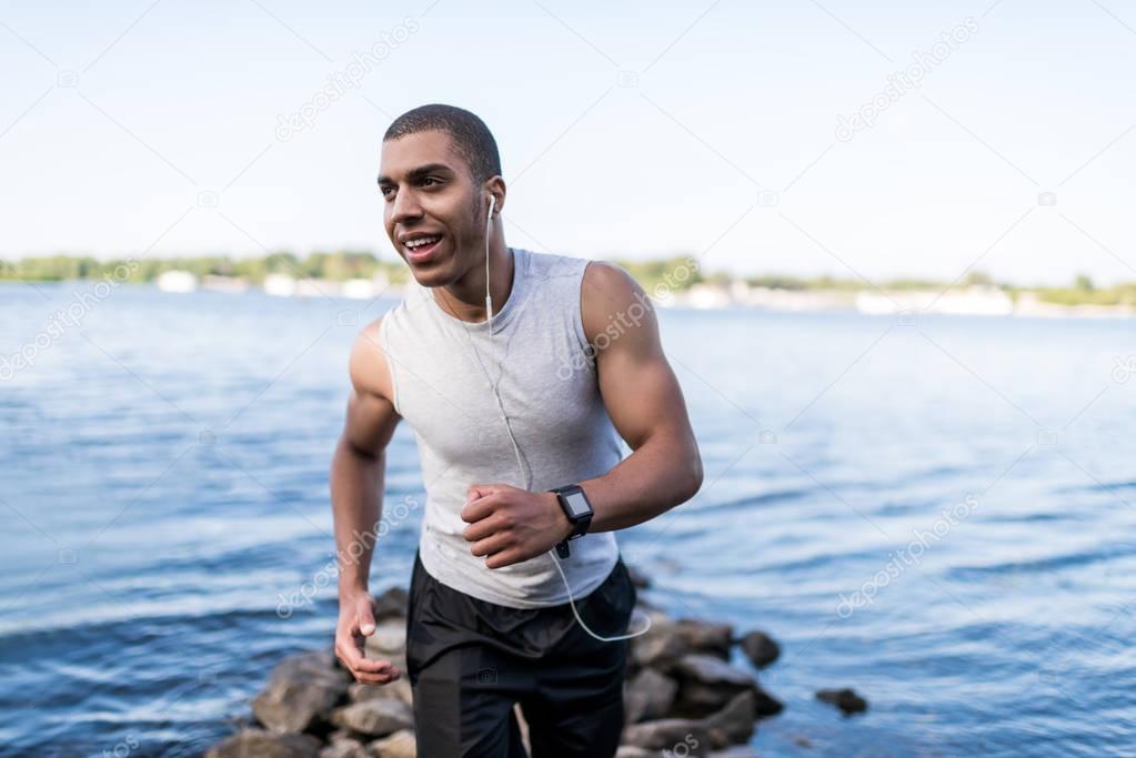 african american sportsman running at riverside