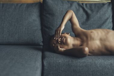 Kanepenin üzerinde oynayan gömleksiz küçük çocuk