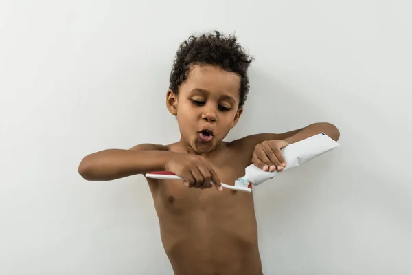 Niño aplicando pasta dental en el cepillo — Foto de Stock