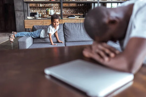 Niño jugando mientras padre sobrecargado de trabajo durmiendo — Foto de Stock