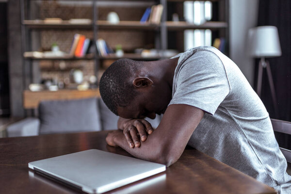 overworked man sleeping near laptop