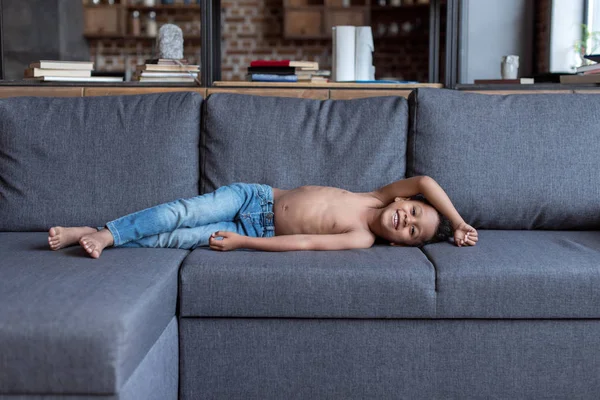 Criança sem camisa brincando no sofá — Fotografia de Stock