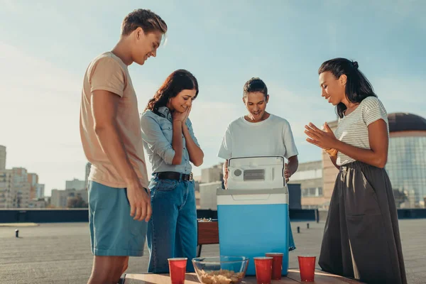 Vrienden kijken naar draagbare koelkast — Stockfoto