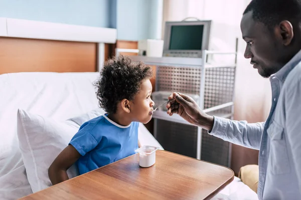 Africano americano padre alimentación hijo — Foto de stock gratuita