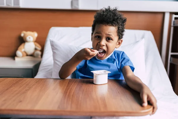 African American boy jedzenie jogurt — Zdjęcie stockowe