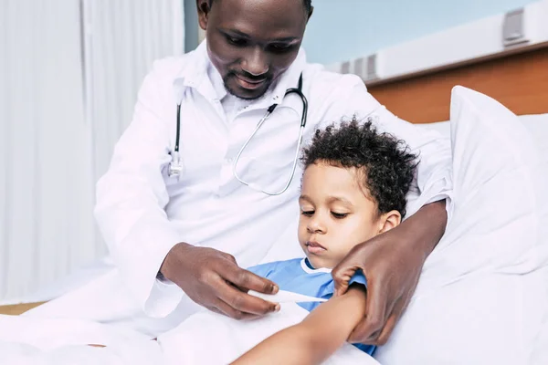 Médico afro-americano medindo a temperatura dos pacientes — Fotografia de Stock