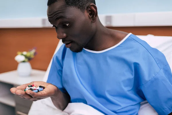 Africano americano hombre mirando píldoras —  Fotos de Stock