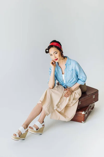 Азиатка, сидящая на багаже — стоковое фото