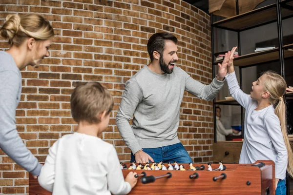 Föräldrar och barn spela bordsfotboll — Stockfoto