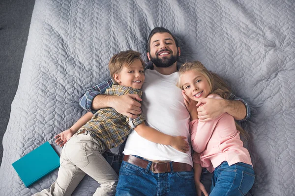 Отец и дети отдыхают на кровати — стоковое фото