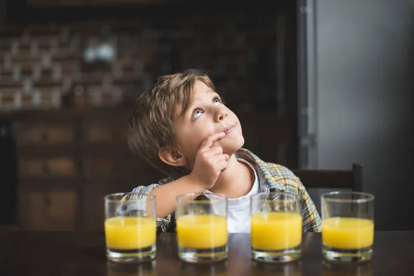 Niño en la mesa con vasos de jugo — Foto de Stock