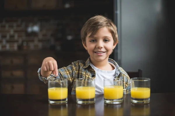 Criança à mesa com copos de suco — Fotografia de Stock
