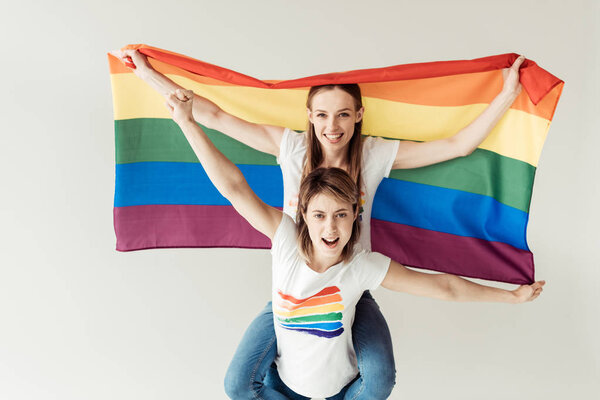Woman giving piggyback to girlfriend with flag