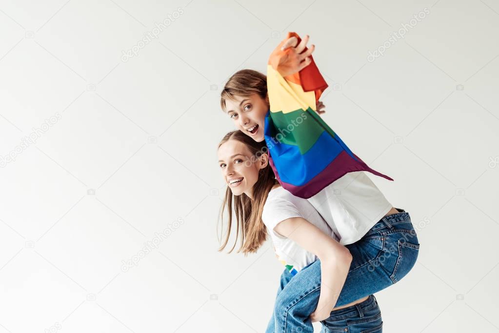 Woman giving piggyback to girlfriend with flag
