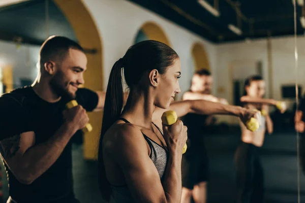 Athletic couple exercising with dumbbells — Stock Photo, Image