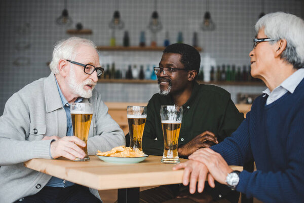 senior friends drinking beer in bar