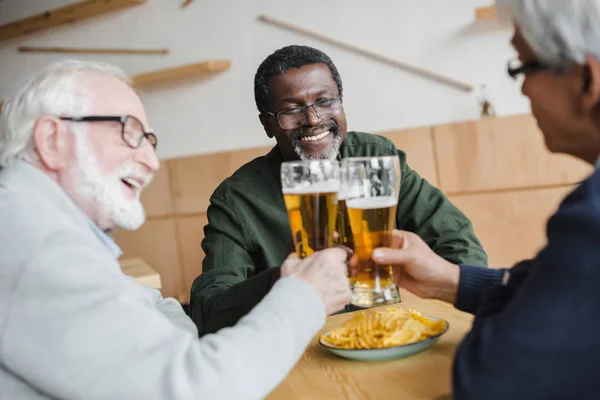 Senior friends clinking glasses of beer — Stock Photo, Image