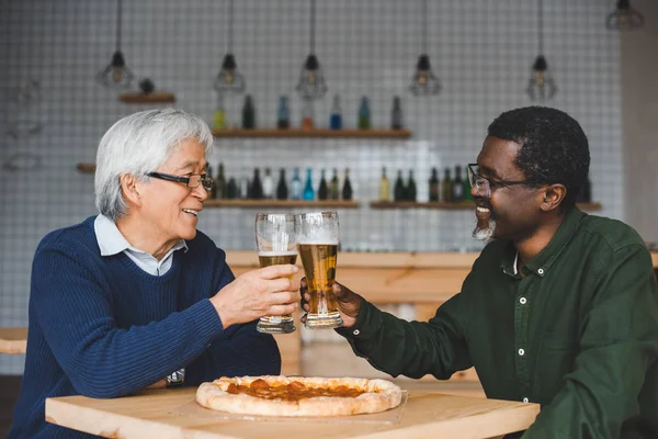 Senior friends clinking glasses of beer — Stock Photo, Image