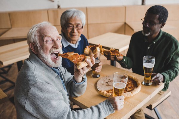 senior friends drinking beer with pizza
