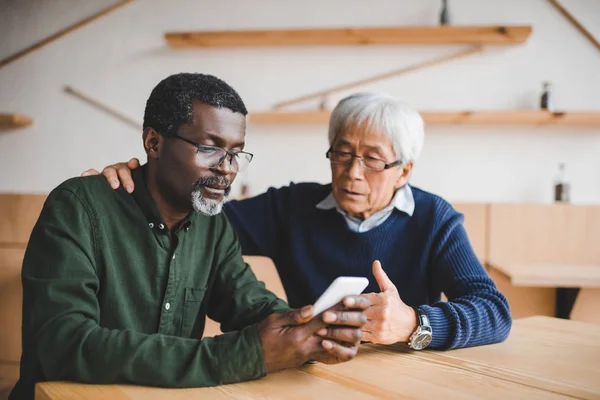 Amigos mayores mirando el teléfono inteligente — Foto de Stock