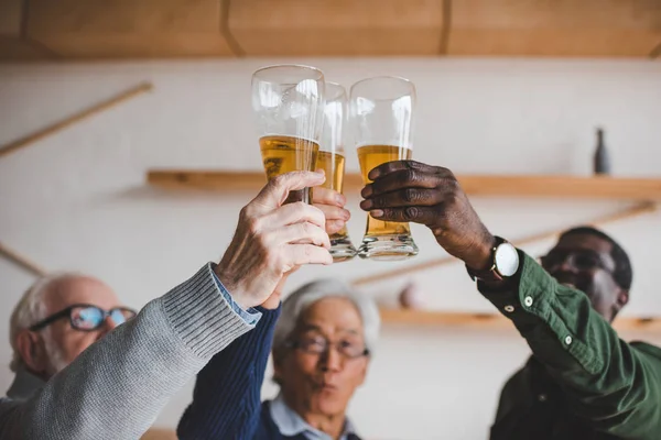 Amigos mayores tintineo vasos de cerveza —  Fotos de Stock