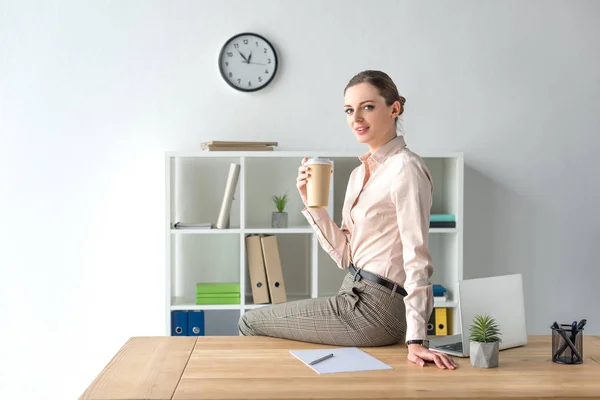 Businesswoman sitting on table with coffee — Stock Photo, Image