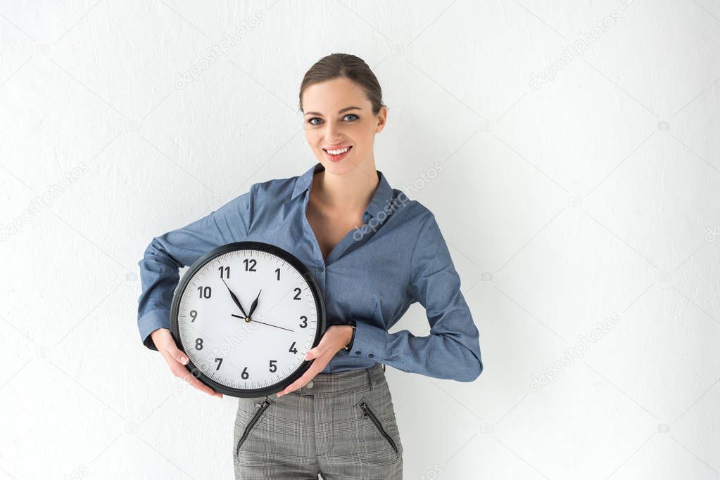 businesswoman holding wall clock in hands