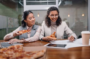 pizza yiyor ve ofiste çok ırklı iş kadınları