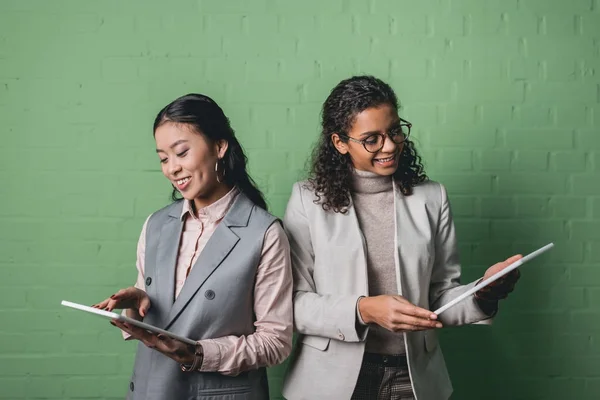 Африканские Американские Азиатские Предпринимательницы Используют Цифровые Планшеты Перед Зеленой Стеной — Бесплатное стоковое фото