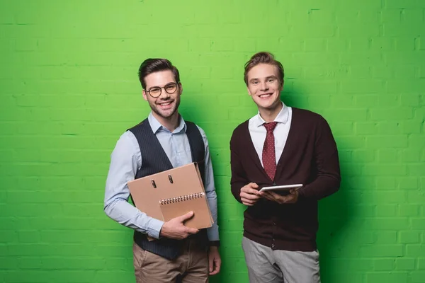 Молоді Усміхнені Бізнесмени Цифровим Планшетом Документами Перед Зеленою Стіною — стокове фото