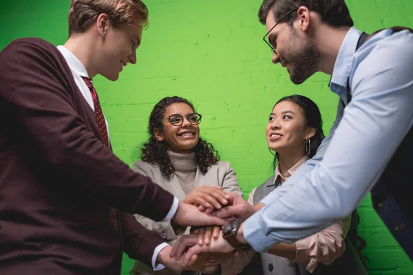 Fröhliches Multiethnisches Geschäftsteam Hält Vor Grüner Wand Die Hände Zusammen — Stockfoto