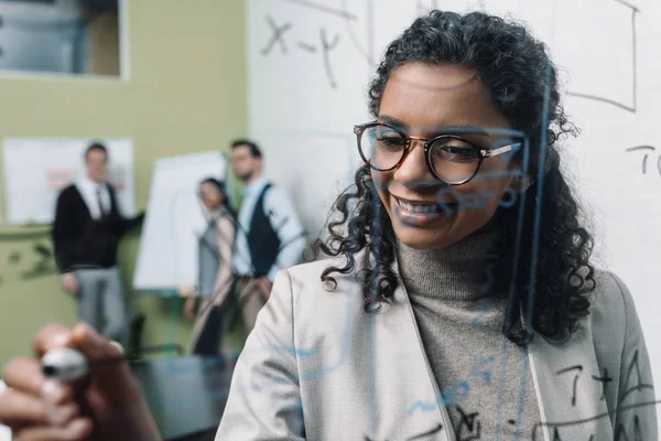 微笑的非洲裔美国女实业家在办公室玻璃板工作 — 图库照片