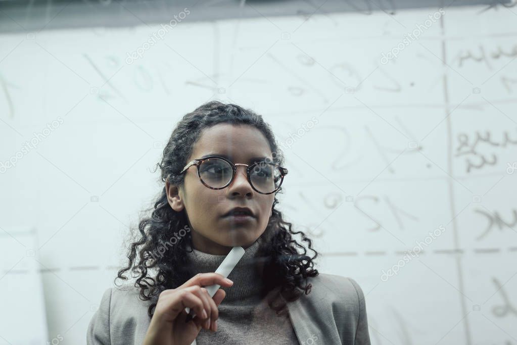 african american businesswoman working with glass board in office