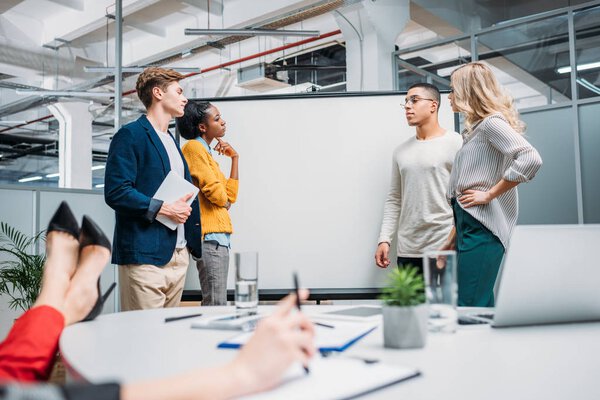 business partners standing in front of presentation board and having conversation