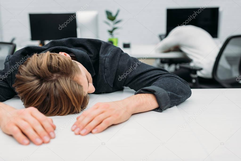 overworked young manager sleeping on work at modern office