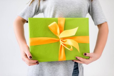 partial view of woman holding wrapped present in hands isolated on grey clipart