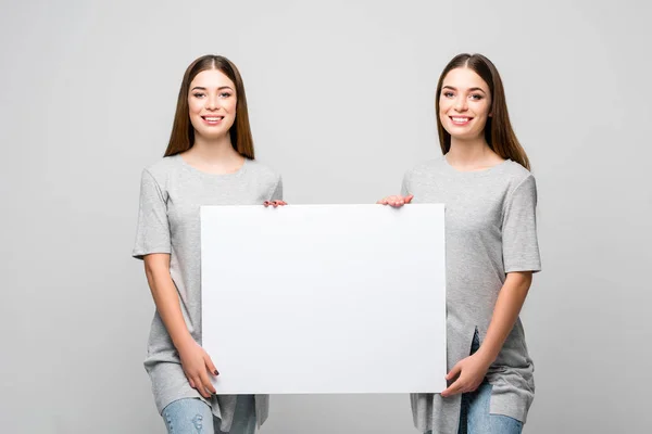 Retrato Belos Gêmeos Sorridentes Segurando Banner Branco Mãos Isoladas Cinza — Fotografia de Stock