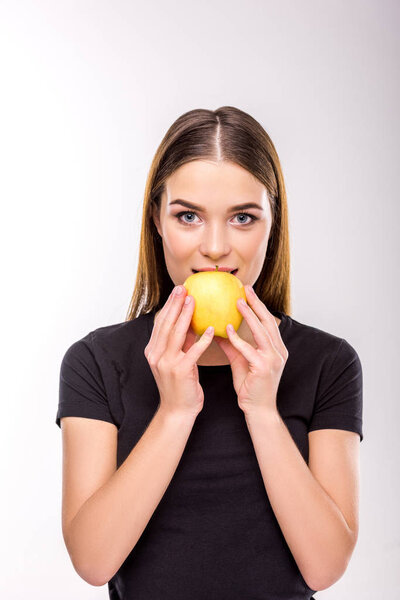 portrait of beautiful woman looking at camera while biting apple