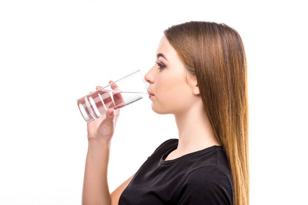side view of young woman drinking water from glass isolated on white