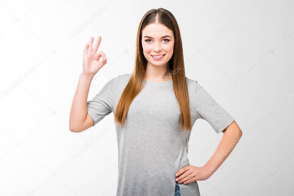 portrait of smiling woman akimbo showing ok sign