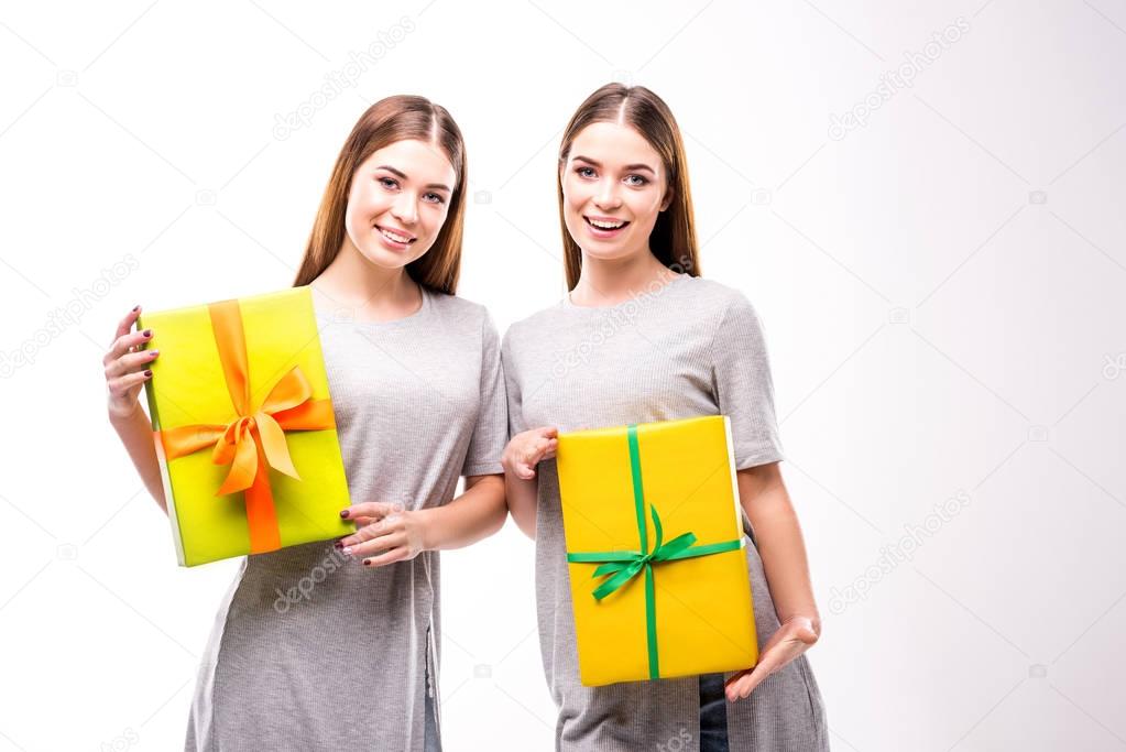 portrait of cheerful twins holding wrapped gifts in hands
