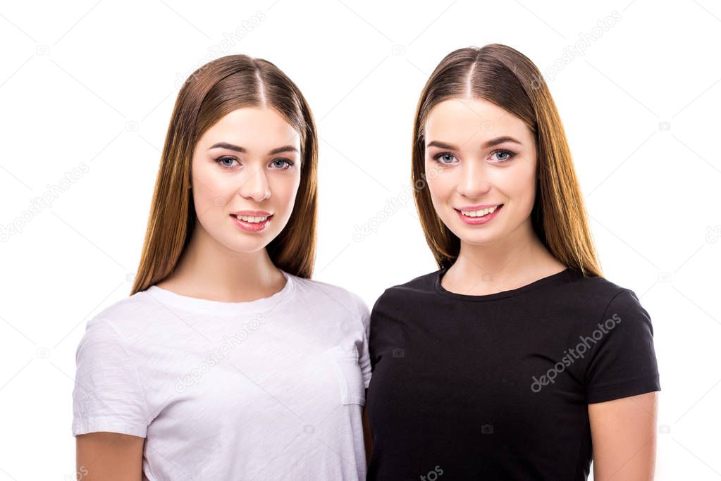 portrait of smiling twins in black and white stylish clothing isolated on white