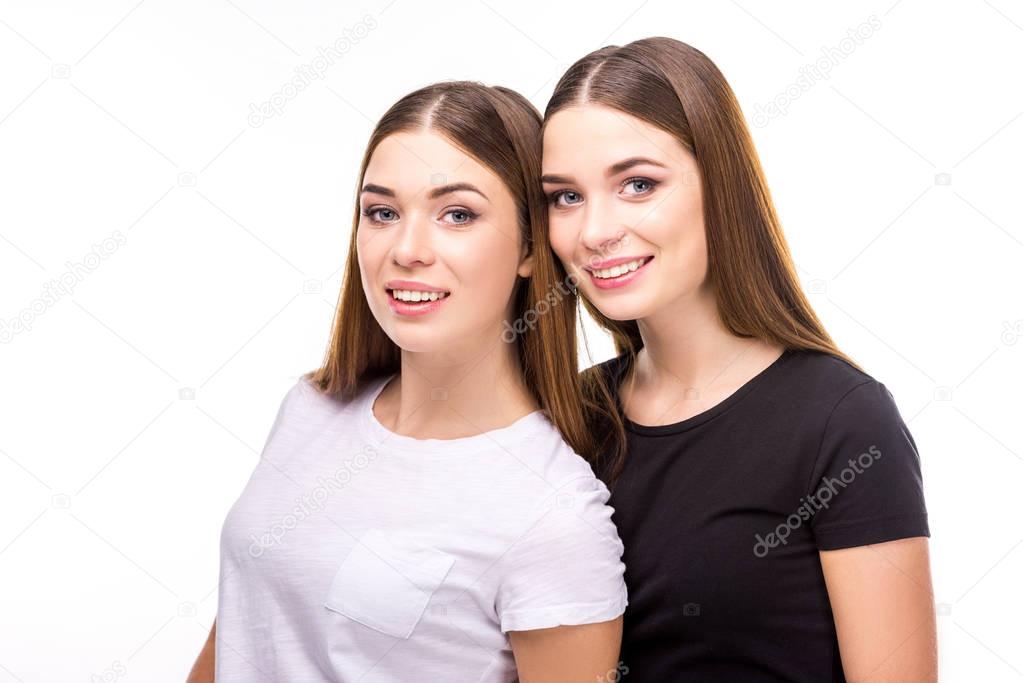 portrait of smiling twins in black and white stylish clothing isolated on white