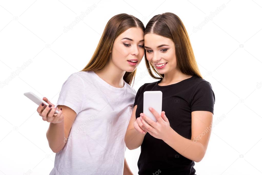 portrait of beautiful twins with smartphones isolated on white