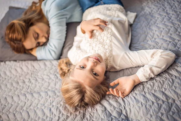 Madre e hija acostadas en la cama - foto de stock