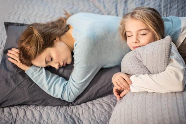 Madre e hija acostadas en la cama - foto de stock