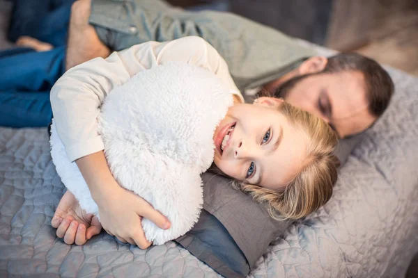 Padre e hija acostados en la cama - foto de stock